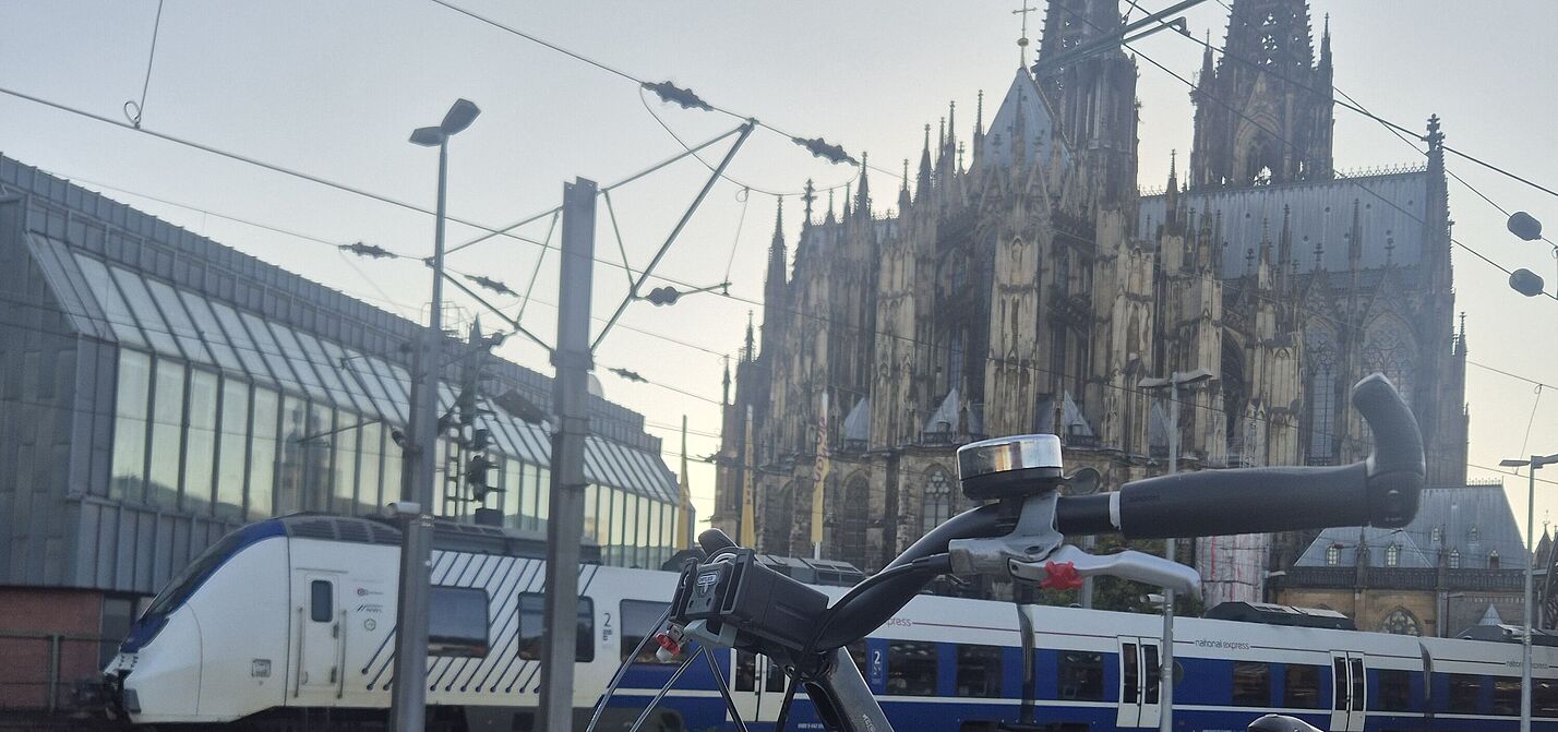 Nahverkehrszug am Hauptbahnhof in Köln. Fahrrad auf Bahnsteig. Dom im Hintergrund.