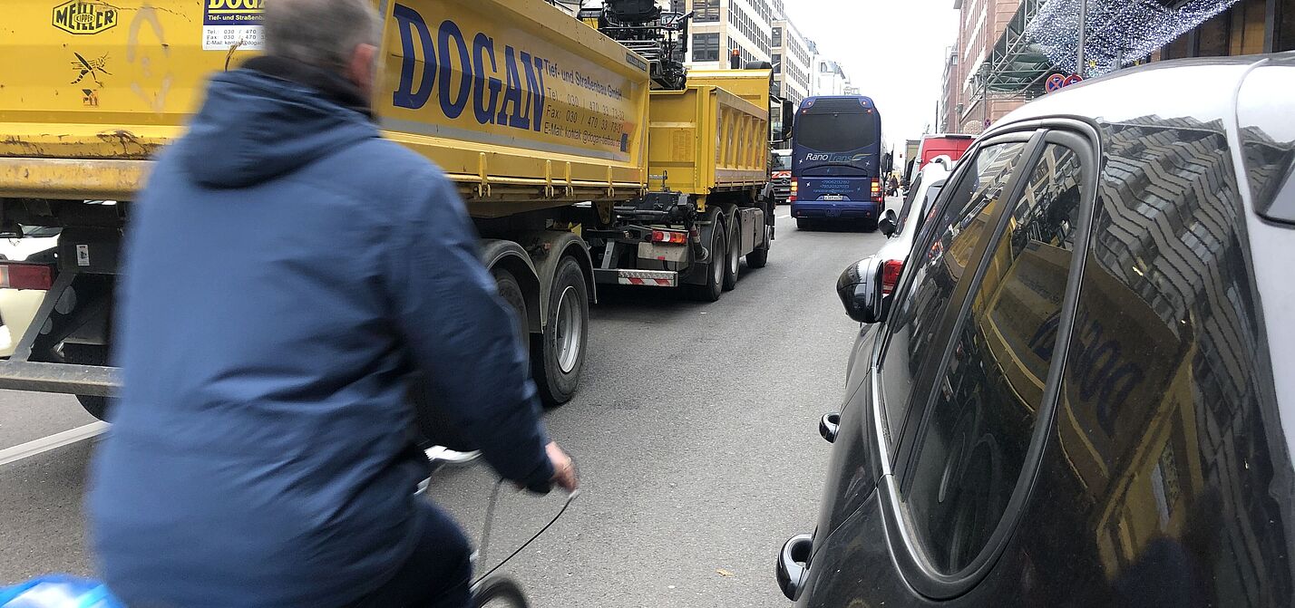 Man fährtzwischen LKW und parkenden Autos Rad